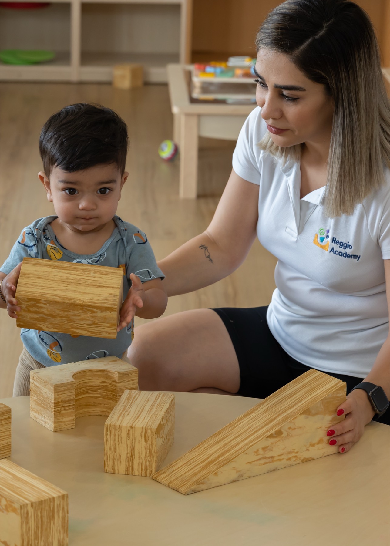 An educator building with blocks alongside a toddler