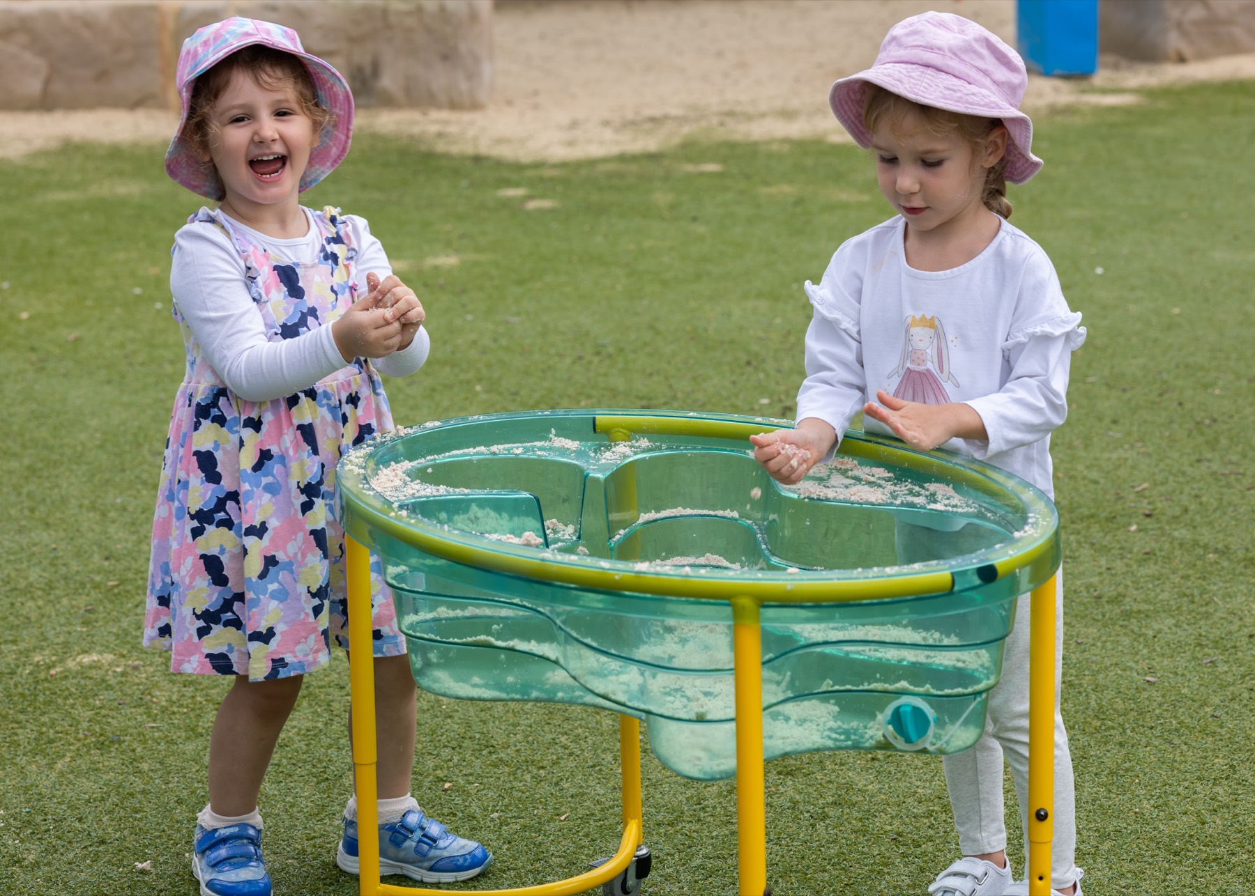 A child laughing at the water table outdoors