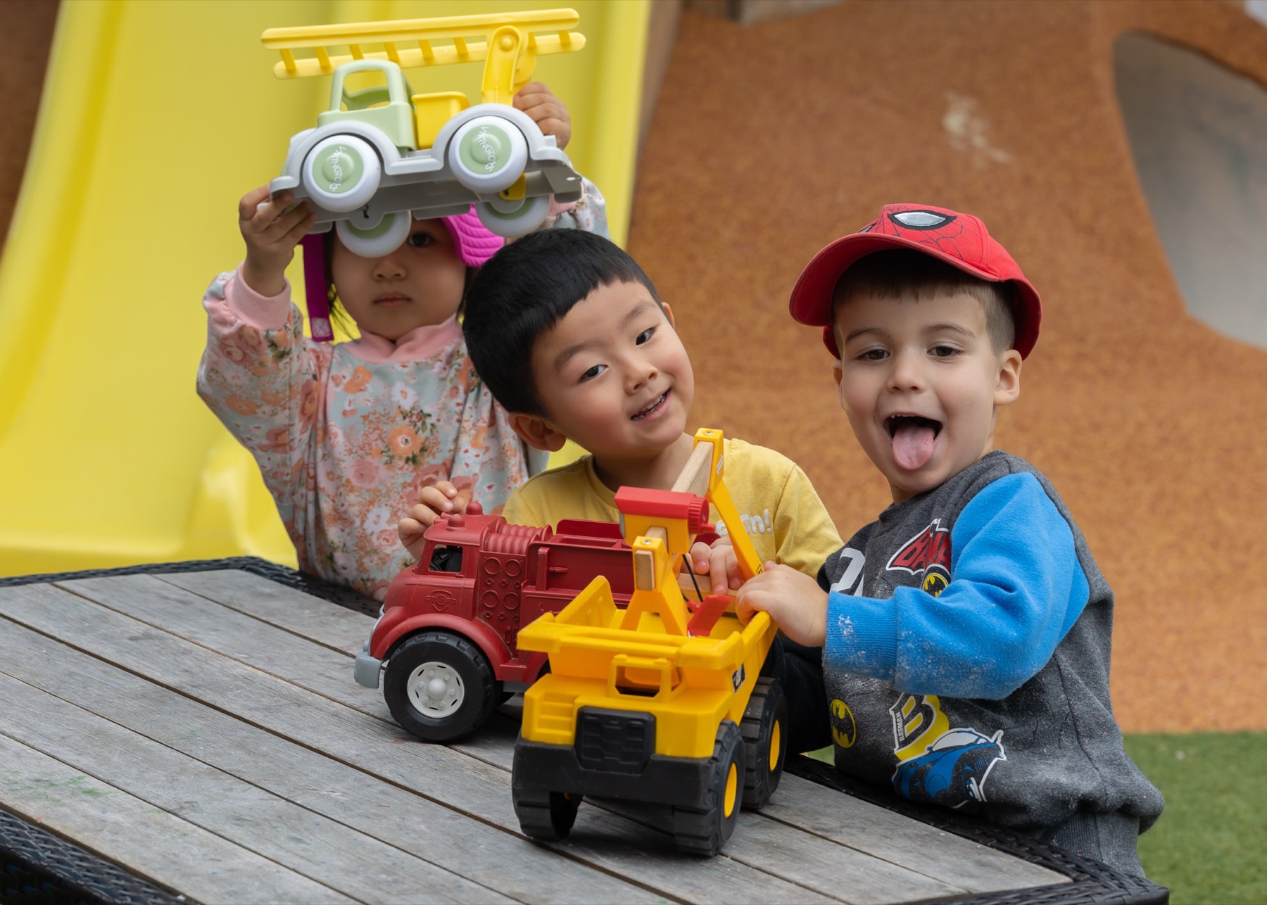 Children laughing over toy trucks outdoors